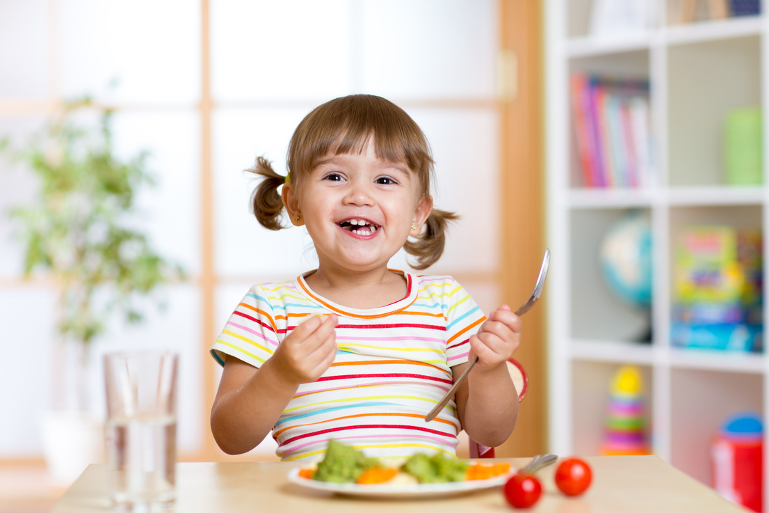 Happy child girl eating vegetables. Healthy nutrition for kids
